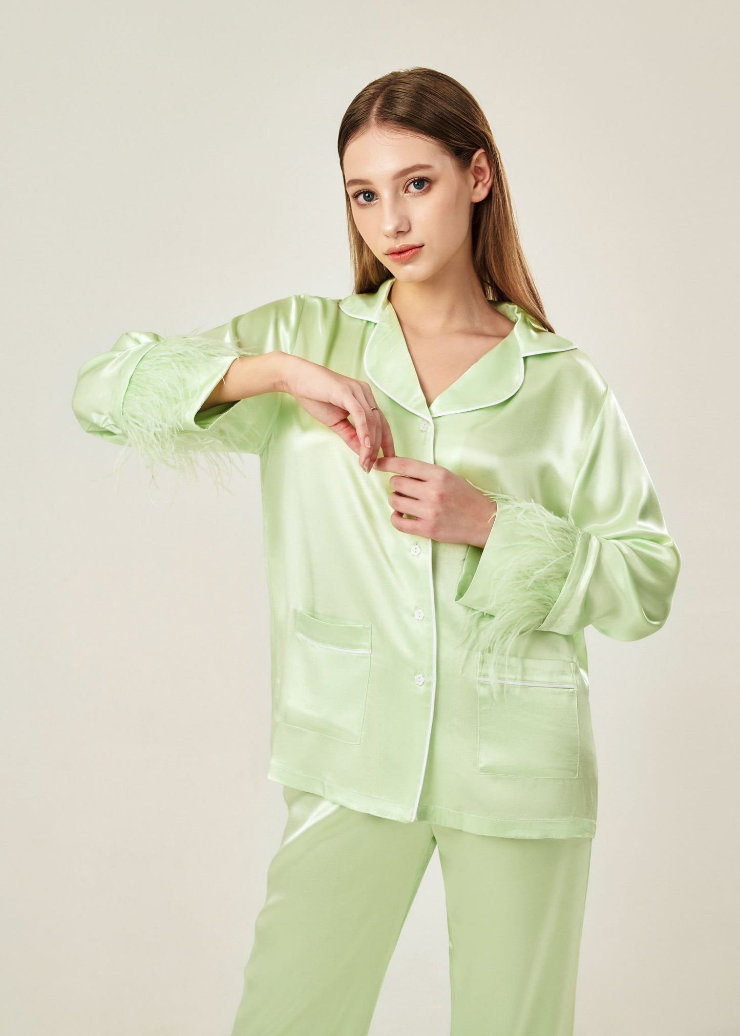 Detail view of lime cream viscose mix rayon pajama set featuring a classic collar, floral buttons, and two front pockets. The detachable ostrich feather trim on the cuffs and pant hems adds a luxurious touch to the relaxed silhouette.