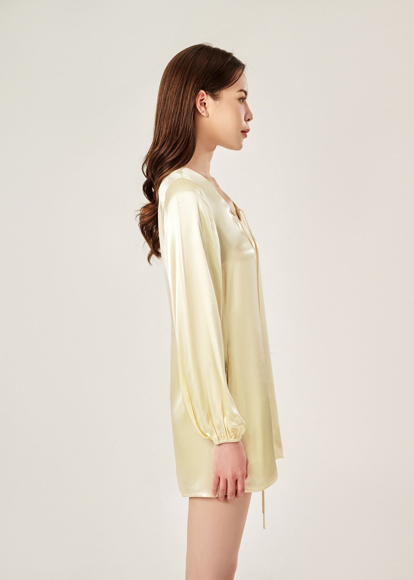 Side view of Cheries Apparel midi shirt dress in beige , featuring puffed long sleeves, a V-neckline with double-needle stitching, and hidden pockets
