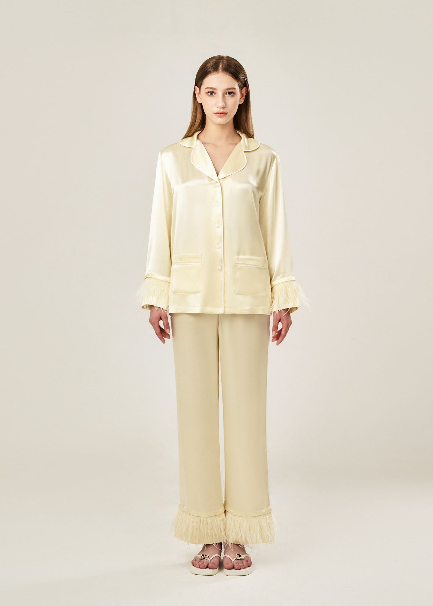 Front view of beige viscose mix rayon pajama set featuring a classic collar, floral buttons, and two front pockets. The detachable ostrich feather trim on the cuffs and pant hems adds a luxurious touch to the relaxed silhouette.