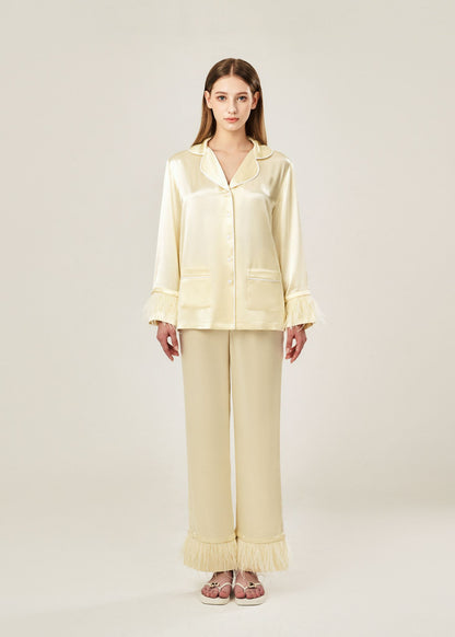 Front view of beige viscose mix rayon pajama set featuring a classic collar, floral buttons, and two front pockets. The detachable ostrich feather trim on the cuffs and pant hems adds a luxurious touch to the relaxed silhouette.