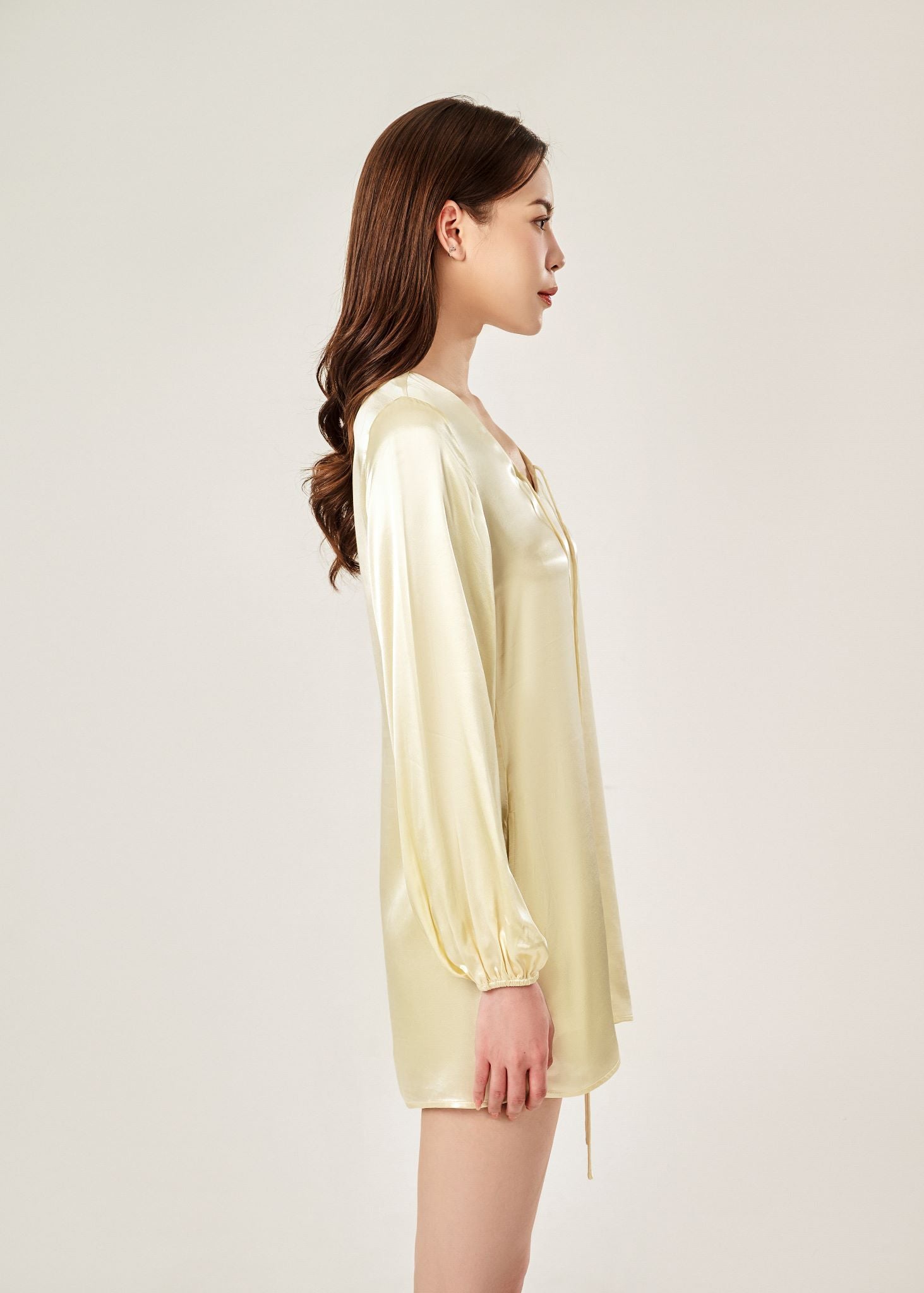 Side view of Cheries Apparel midi shirt dress in beige , featuring puffed long sleeves, a V-neckline with double-needle stitching, and hidden pockets